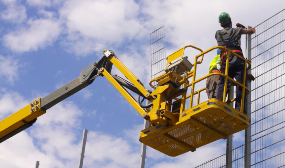 Opérateur portant un harnais de sécurité attaché au point d ancrage du panier de la nacelle.